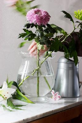 Mujer cambiando el agua de un recipiente de cristal con flores cortadas