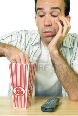3537347 a man eating popcorn while watching a boring movie cine