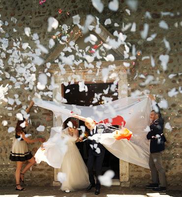 Novios saliendo de la ceremonia mientras atraviesan un lienzo y les lanzan confetti