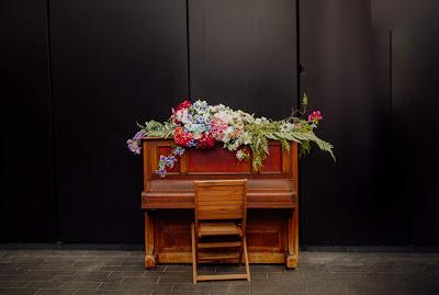 Piano decorado con flores y una silla vacía delante del teclado