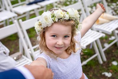 Niña vestida para una boda de la mano de su padre señalándole algo con una sonrisa