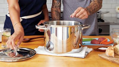 Dos personas cocinando con una olla de aluminio