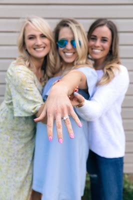 Novia enseñando su anillo de compromiso con amigas a los lados