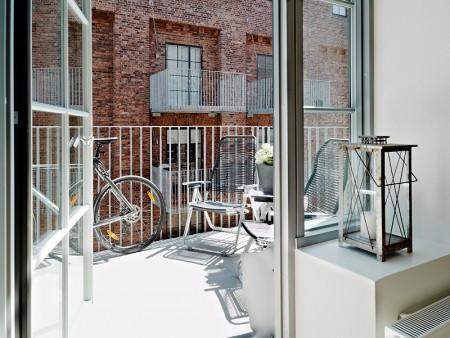 Aires de loft en un sexto piso vigas de metal piso nórdico muebles de balcón loft lámparas de estilo industrial grandes ventanales diseño de interiores decoración sueca decoración nórdica cocinas modernas cocinas blancas barra en la cocina