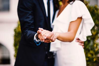 Foto preboda de novios, ella con un vestido blanco y enseñando el anillo