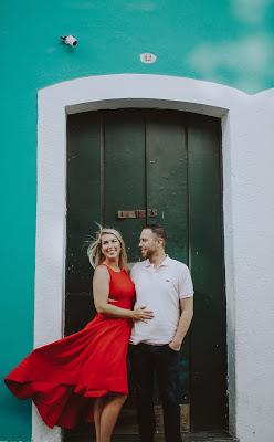 Pareja de novios delante de una puerta, ella con un vestido rojo y el cabello suelto