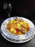 Plato de caldereta de conejo y copa de vino tinto Plato de caldereta de conejo con patatas y copa de vino tinto.