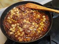 Agregando los garbanzos cocidos al guisode los calamares.