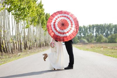 Novios besándose detrás de un parasol