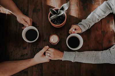 Pareja tomada de la mano mientras toman un café