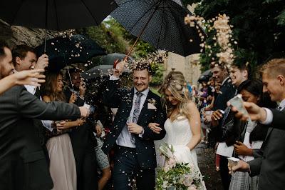 Novios saliendo del lugar de la ceremonia rodeados de invitados que les lanzan confetti