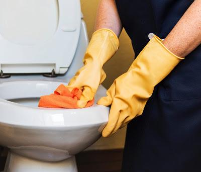 Persona limpiando un inodoro con guantes Persona limpiando un inodoro con guantes