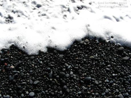 Espuma de mar en la orilla negra