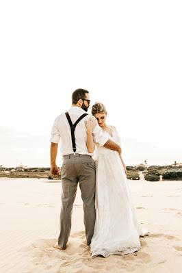 Novios en la playa, ella con vestido con escote en V y recogido