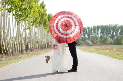 Pareja de novios en medio de una carretera detrás de una sombrilla Pareja de novios en medio de una carretera detrás de una sombrilla