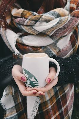 Mujer con bufanda y sosteniendo un café