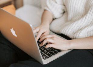 crop woman typing on laptop on bed