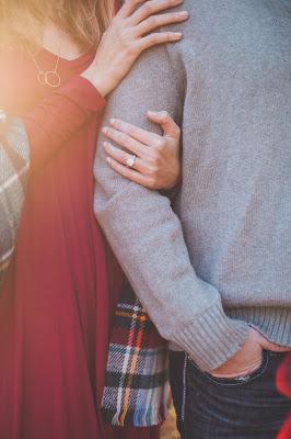 Pareja tomada del brazo, ella con un anillo de compromiso en el dedo