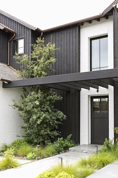 wicker patio furniture surf-inspired décor sliding glass doors outdoor fireplace open floor plan Newport Beach moody color scheme interiores abiertos interactive rooms industrial details gray sectional sofa estilo californiano decoración moderna decoración americana coastal décor charcoal gray decor california brass accessories backyard decor  