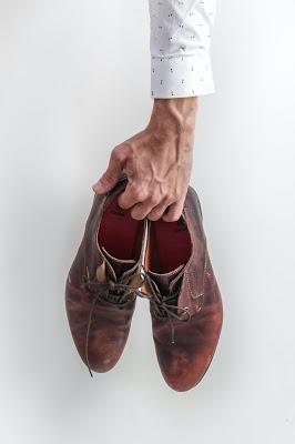 Mano masculina sosteniendo un par de zapatos