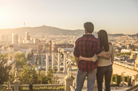 Young couple looking sunset in Barcelona, they are embracing and looking to the cityscape from Montjuic.