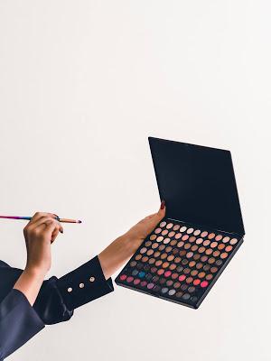 Mujer eligiendo entre las sombras de una paleta de maquillaje Mujer eligiendo entre las sombras de una paleta de maquillaje