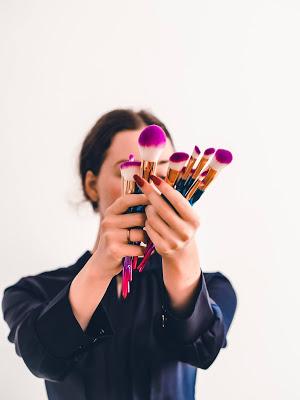 Mujer mostrando un conjunto de brochas de maquillaje