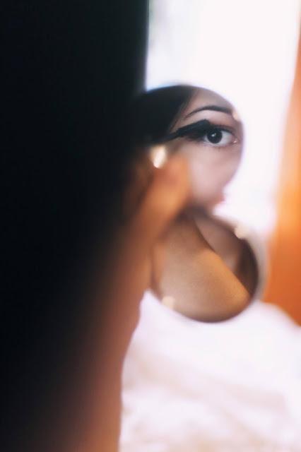 Mujer aplicándose rímel delante de un espejo