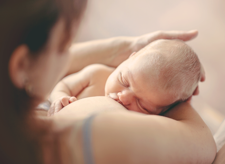 ¿Qué es una asesora de lactancia? Madre de espaldas dando el pecho a su bebé recién nacido mientras el sostiene la cabeza suavemente