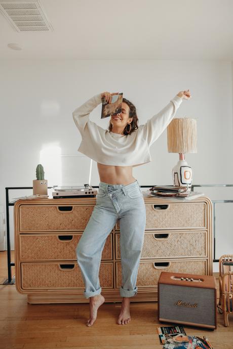 Must-loved denim wearing Agolde jeans and cropped sweatshirt at home