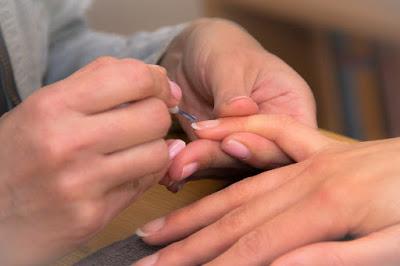 Manicurista aplicando base