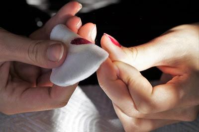 Mujer eliminando el esmalte de uñas con quitaesmaltes Mujer eliminando el esmalte de uñas con quitaesmaltes