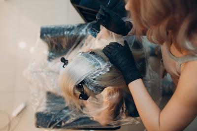 Mujer debajo de una capa de plástico mientras se aplican mechas en el pelo