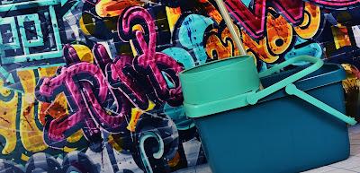 Cubo de fregona delante de una pared con graffities Cubo de fregona delante de una pared con graffities