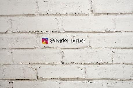 Detalle del mural de ladrillo blanco con la cuenta de Instagram del peluquero