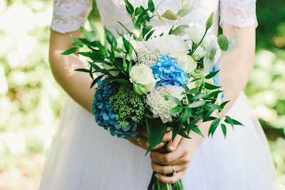 Novia llevando en las manos un ramo con flores azules