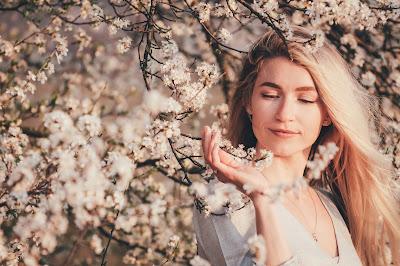 Mujer rubia con melena XXL y rodeada de ramas de un árbol en flor Mujer rubia con melena XXL y rodeada de ramas de un árbol en flor