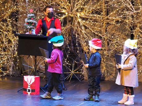 tres niĂąos disfrutan en el escenario del espectĂĄculo de magia de Vila Natal, en Ăbidos, Portugal
