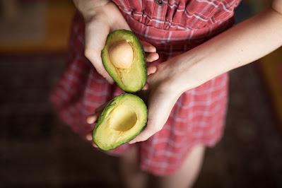 Mujer sosteniendo dos mitades de un aguacate Mujer sosteniendo dos mitades de un aguacate