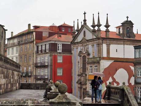 dos personas con paraguas frente a la iglesia san nicolas oporto