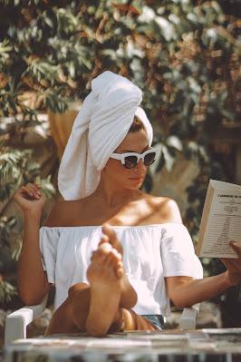Mujer tomando el sol con una toalla en la cabeza y gafas de sol