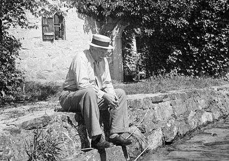 Swiss psychiatrist Dr_ Carl Jung pensively sitting on stone wall outside his home in Knusnacht, Switzerland, 1949
