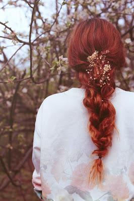 Mujer con melena pelirroja, con trenza adornada con flores