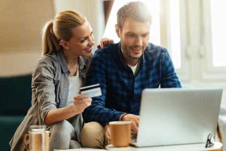 Happy couple shopping online with credit card and laptop at home