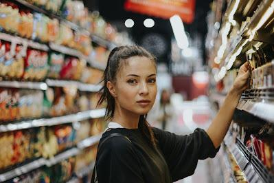 Mujer tomando un producto de un lineal del supermercado