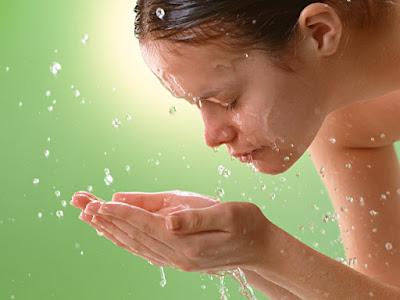 Mujer aclarándose el rostro con agua