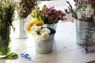 Mesa con cubos de zinc con flores y tijeras