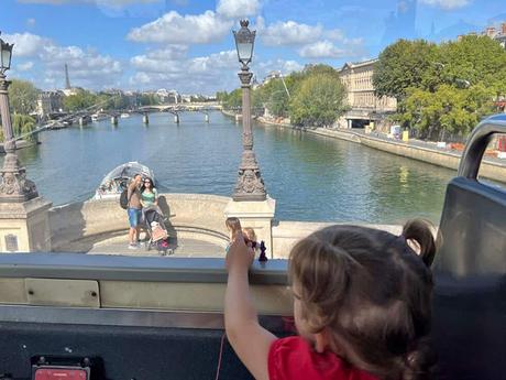 Una niña viendo el río Sena desde lo alto de un autobús turístico de París.