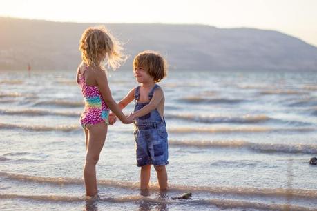 5 prendas de ropa imprescindibles para vestir a bebés y niños en verano niño y niña disfrtando en la playa