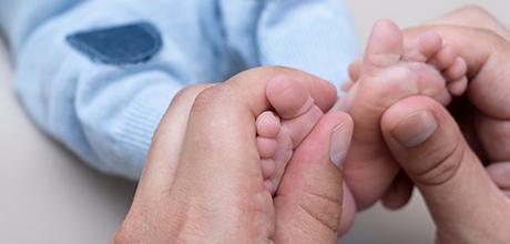 Manos de una mamá cogiendo pies de bebé - Baja de maternidad o paternidad de un autónomo